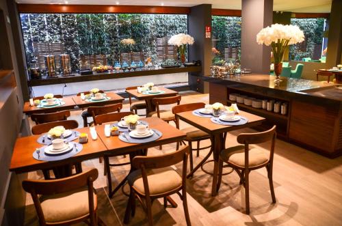 um restaurante com mesas e cadeiras de madeira e um balcão em Hotel Cercano em Gramado