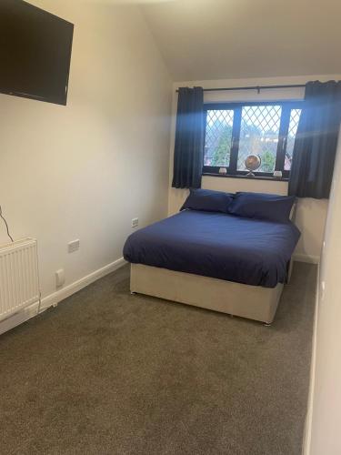 a bedroom with a bed with blue pillows and a window at 5 bedroom modern detached house in Morriston