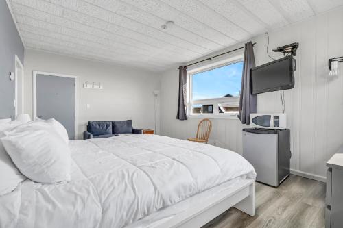 - une chambre avec un grand lit blanc et une fenêtre dans l'établissement Cape View Motel & Cottages, à Mavillette