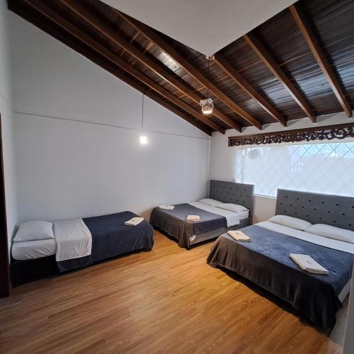 um quarto com 2 camas e piso em madeira em Fortaleza Diosa Chia em Chía
