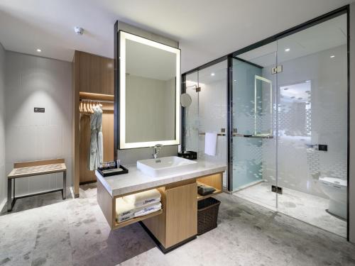 a bathroom with a sink and a glass shower at Hampton by Hilton Guangzhou Baiyun Airport North in Huadu