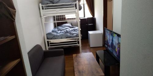 ein kleines Zimmer mit einem Etagenbett und einem Tisch in der Unterkunft スターリースカイズ那須店 in Nasu