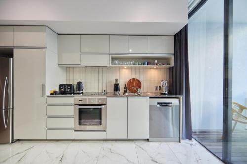 a kitchen with white cabinets and stainless steel appliances at Pavilions Marina Apartment 102 - Wynyard Quarter Viaduct Harbour in Auckland