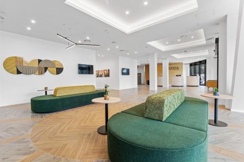 a lobby with two green couches and two tables at La Quinta by Wyndham Ellerslie Auckland in Auckland