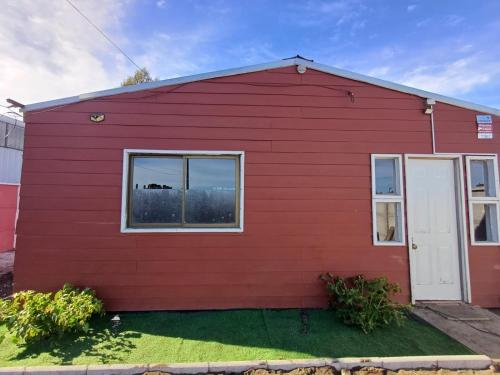 una casa rossa con porta bianca e finestre di Cabañas con tinajas coronel a Coronel