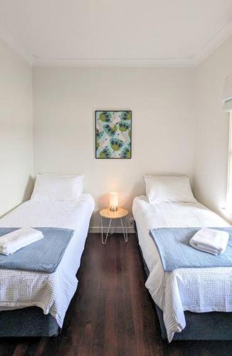 two beds in a room with a table with a candle at Charming Large Home: Modern Comfort and Convenience in Carey Park