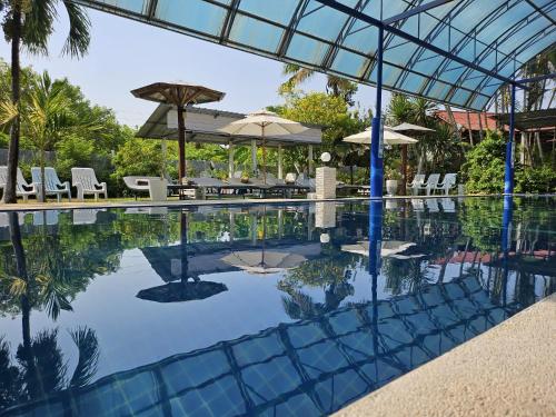 a swimming pool with chairs and umbrellas at Thai Garden​ Resort​ Kanchanaburi​ in Kanchanaburi