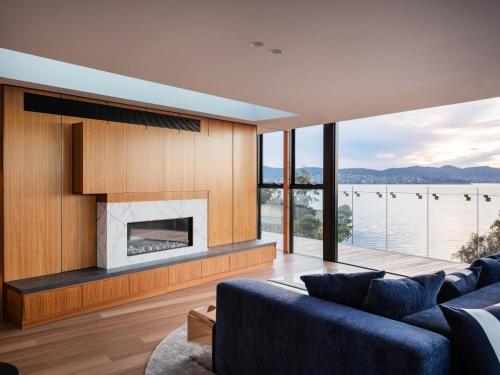 a living room with a blue couch and a fireplace at 'Hobart' - Waterfront penthouse with private heated pool in Hobart
