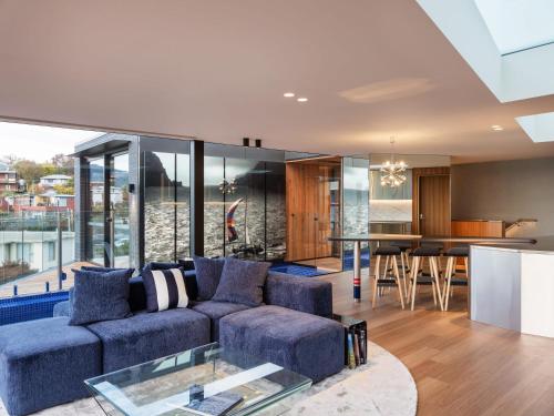 een woonkamer met een blauwe bank en een tafel bij 'Hobart' - Waterfront penthouse with private heated pool in Hobart