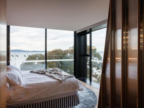 een slaapkamer met een bed en een groot raam bij 'Hobart' - Waterfront penthouse with private heated pool in Hobart