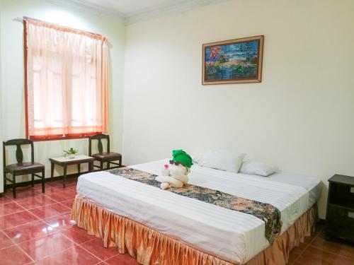 a teddy bear sitting on a bed in a room at Grand Palem Hotel in Songgoriti