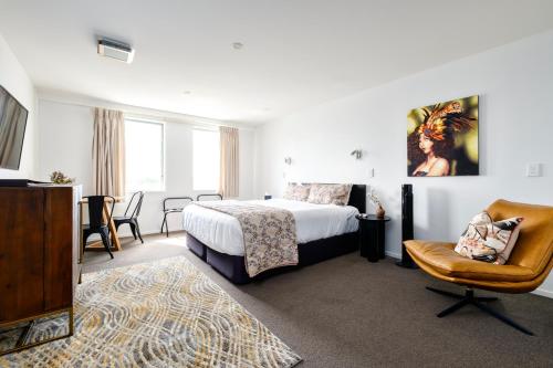 um quarto de hotel com uma cama e uma cadeira em Cathedral Junction Apartments em Christchurch