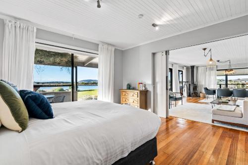 a bedroom with a large bed and a living room at Stargazers Waterfront Hot tub Cottage Tasmania in Clarence Point