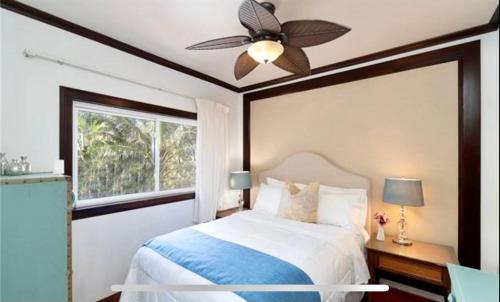 a bedroom with a bed with a ceiling fan and a window at Tropical Paradise…pristine sandy beaches and clear blue water in Waimanalo