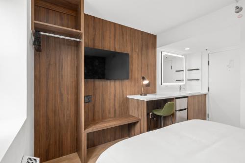 1 dormitorio con paneles de madera, 1 cama y escritorio en Uptown Inn by Vantaggio Suites en San Diego
