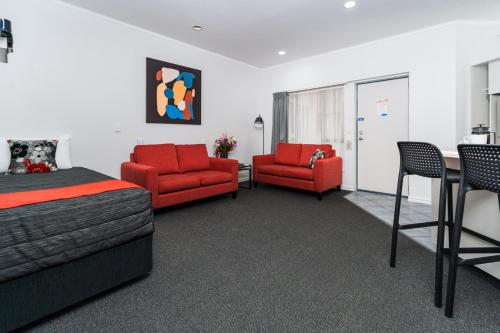 a room with a bed and two chairs and a table at Aubyn Court Spa Motel in Palmerston North