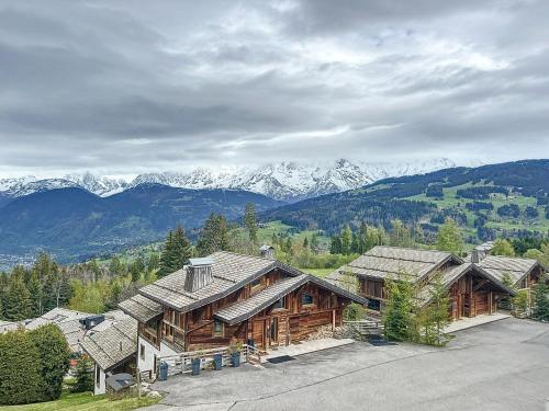 une grande cabane en rondins avec des montagnes en arrière-plan dans l'établissement Studio cosy aux pieds des pistes avec parking à Combloux - FR-1-560-137, à Combloux