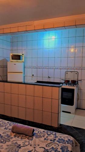 a tiled kitchen with a stove and a microwave at kitnet casa completa in Guarulhos