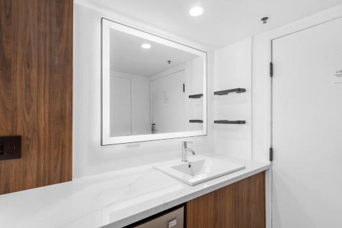 a white bathroom with a sink and a mirror at Uptown Inn - Limited Service Apart-Hotel in San Diego