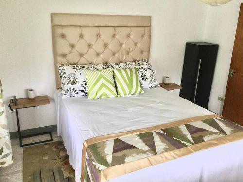 a bedroom with a large bed with green and white pillows at Serenity 2-Bed Apartment in Port Antonio in Port Antonio