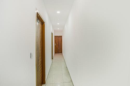 バティンダにあるOYO Dr Plazaの白い壁の廊下、ドア、タイルフロア