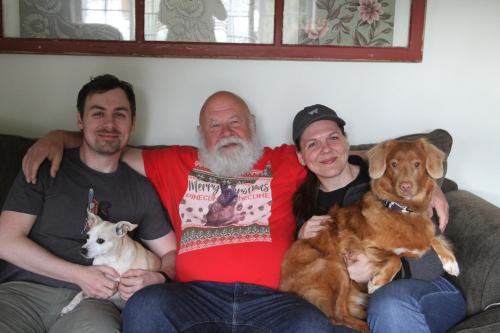 tres hombres sentados en un sofá con sus perros en Sunshine and Wine Loft en Penticton