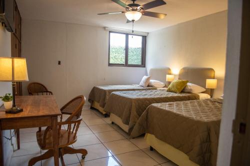 a bedroom with two beds and a table and a desk at Villa Nola in Guatemala