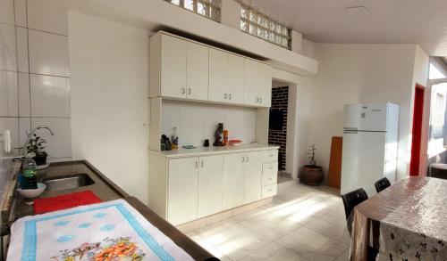 a kitchen with white cabinets and a sink and a refrigerator at Matianellu SP in São Paulo