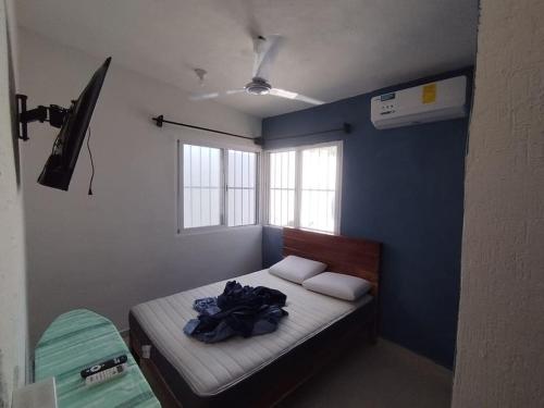 a small bedroom with a bed with a blue wall at La casa de los Pajaritos in Chetumal
