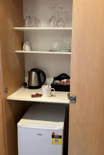 a pantry with a tea pot and a cup on a shelf at Auto Lodge in New Plymouth
