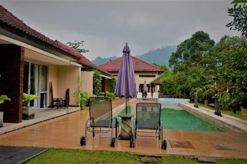 patio con tavolo, ombrellone e piscina di Villa Kendi a Banyuwangi