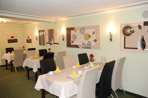 a dining room with white tables and white chairs at Hotel Post in Scheidegg