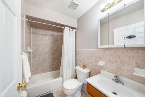 y baño con aseo blanco, lavabo y bañera. en Convenient Getaway - Shared Family Home en Newark