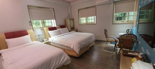 新埔鎮的住宿－霽月山莊，酒店客房带两张床和一张桌子以及椅子。