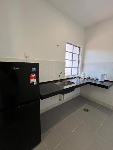 uma cozinha com um lavatório e um frigorífico preto em Seruni Apartment em Serendah