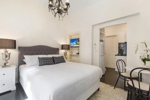 a bedroom with a white bed and a table and chairs at Chic CBD Studio in Heritage House with Pool & BBQ in Melbourne