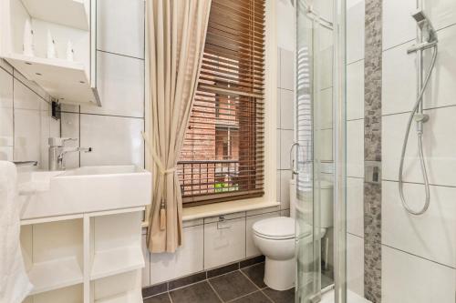 a bathroom with a toilet and a sink and a window at Chic CBD Studio in Heritage House with Pool & BBQ in Melbourne