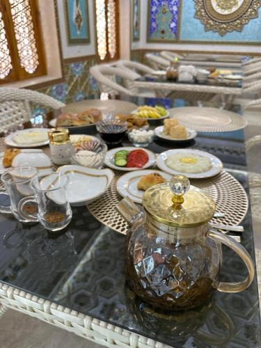 a table with plates of food and a vase on it at Hotel Khalid in Bukhara
