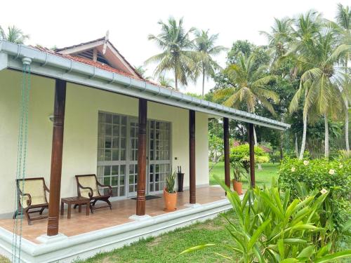 a porch of a house with two chairs and palm trees at Tamarind Tree Garden Resort - Katunayake in Negombo