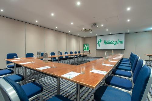 a conference room with a long table and blue chairs at Holiday Inn - Glasgow Airport by IHG in Paisley