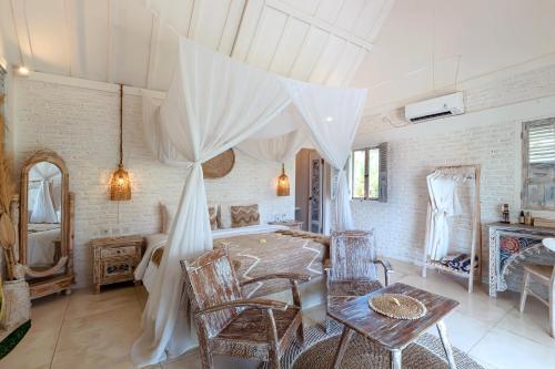 a room with a bed and a table and chairs at Atalaya Villas Nusa Penida - Adults only in Nusa Penida