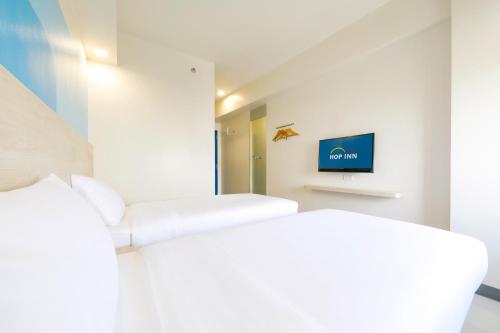 a white room with a couch and a tv at Hop Inn Hotel Iloilo in Iloilo City