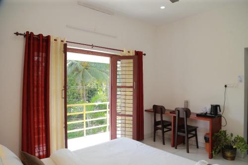 a bedroom with a bed and a table and a window at raison d'être - The Residential Library in Trivandrum