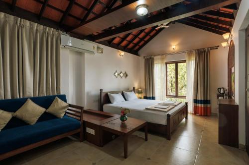 a bedroom with a bed and a couch and a table at Sai Vishram Beach Resort in Baindūru