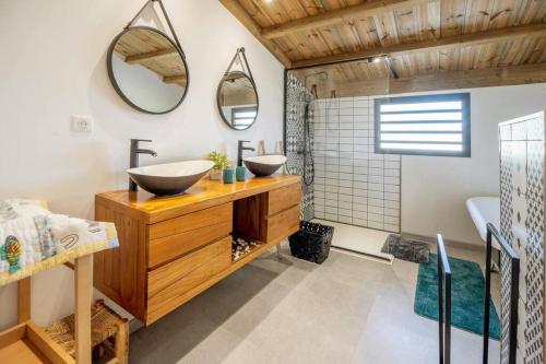 a bathroom with two sinks and two mirrors at Villa Nauraa - 5ch - piscine - proche plage. in Trois Bassins
