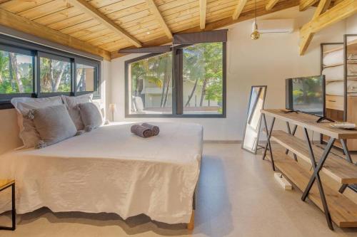 a bedroom with a bed and a desk and windows at Villa Nauraa - 5ch - piscine - proche plage. in Trois Bassins