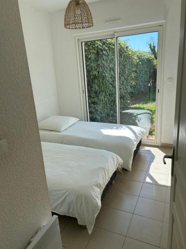 a row of beds in a room with a window at Rez de Jardin Piscine et Plage in Poggio-Mezzana
