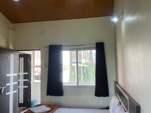 1 dormitorio con una ventana con cortinas azules en Gugal Residency Mahabaleshwar, en Mahabaleshwar