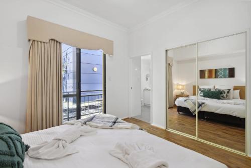 ein Schlafzimmer mit einem Bett und einem großen Spiegel in der Unterkunft 1BDR 1BTH 1PRK - James Street Joy in Perth