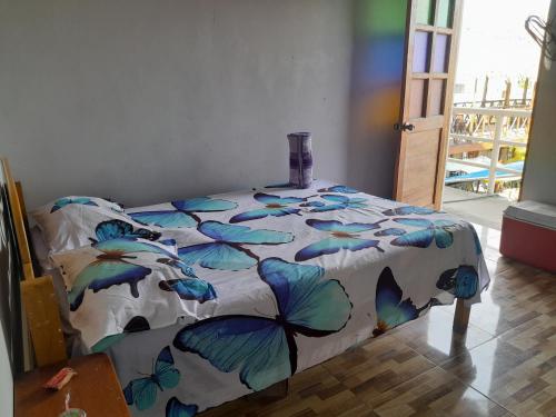 ein Schlafzimmer mit einem Bett mit einer nach Schmetterlingen gemusterten Daunendecke in der Unterkunft El Bunker 9 in Iquitos